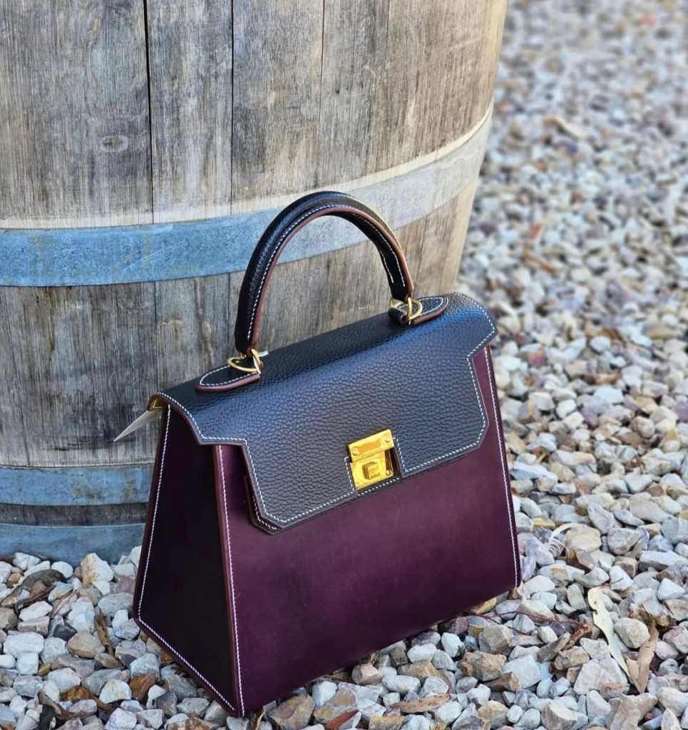 Handcrafted leather bag beside a wooden barrel